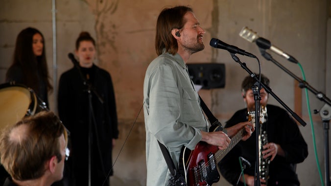 Hayden Thorpe playing guitar and singing with a band behind him in a converted military building on Orford Ness